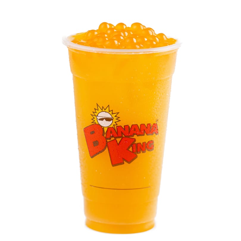 A Banana King mango drink with orange popping boba, condensation on the cup, against a white background.