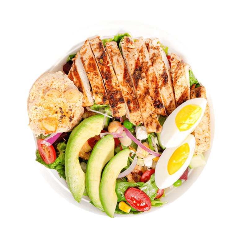Grilled chicken salad with avocado, hard-boiled eggs, hummus, and fresh vegetables from Banana King.