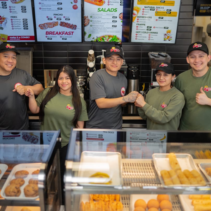 Five Banana King employees in uniform pose behind a counter with menu boards and food displays.