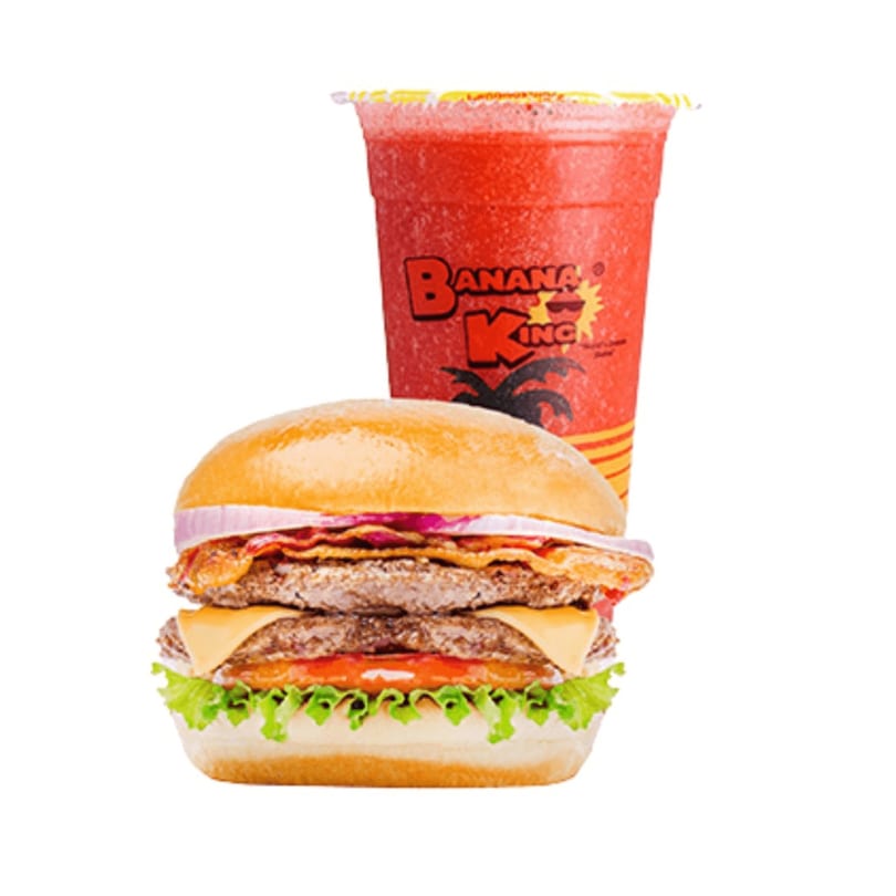 A Banana King double cheeseburger with bacon, onions, and lettuce, next to a red slushy drink.