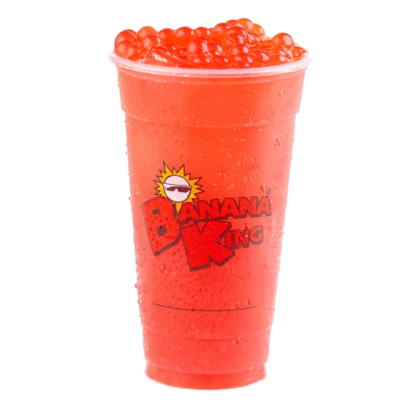 A Banana King red drink with popping boba, condensation on the cup, against a white background.