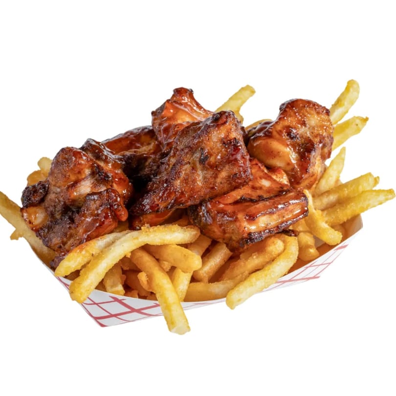 Banana King's BBQ chicken wings and golden french fries in a red and white checkered paper tray.